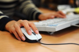 Person using a white computer mouse and keyword